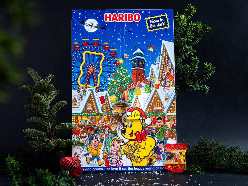 Julekalender fra Haribo med en vinter- og juletema, omgitt av granbar og snø, med en tegneserieaktig illustrasjon av julefigurer og godteri på forsiden.