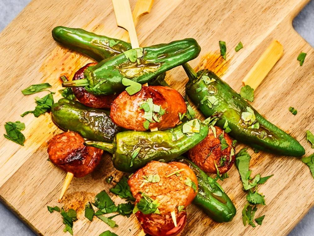 Stekte små grønne chili og tomater med hakket grønn løk på et skjærebrett