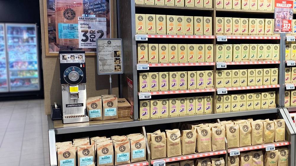 Kaffe på hyller med kaffekvern i bakgrunnen i en butikk