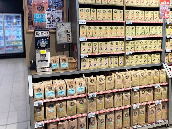 Kaffe på hyller med kaffekvern i bakgrunnen i en butikk