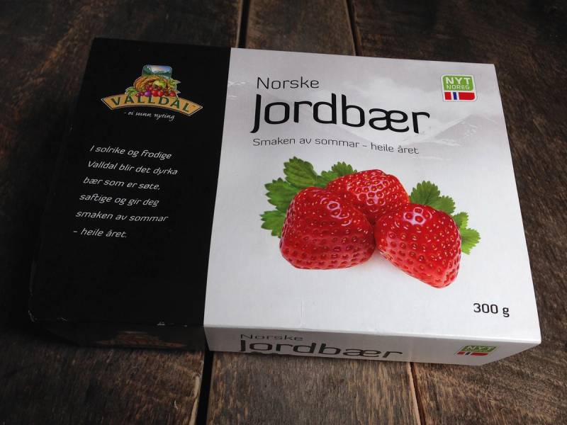 En eske med norske jordbær på en treflate, med teksten 'Norske Jordbær' på boksen.