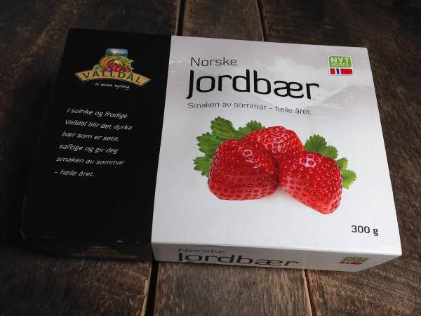 En eske med norske jordbær på en treflate, med teksten 'Norske Jordbær' på boksen.