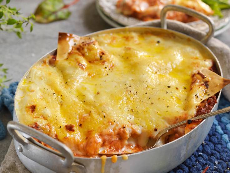 Lasagne med smeltet provoloneost på toppen i en oval ildfast form, klar til servering.