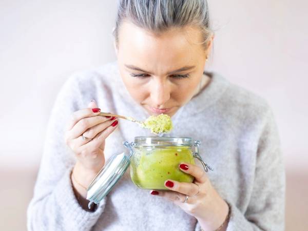 Person som lukter på en grønn frukt eller grønnsak i et glass, med fokus på sansene se, lukt og smak.