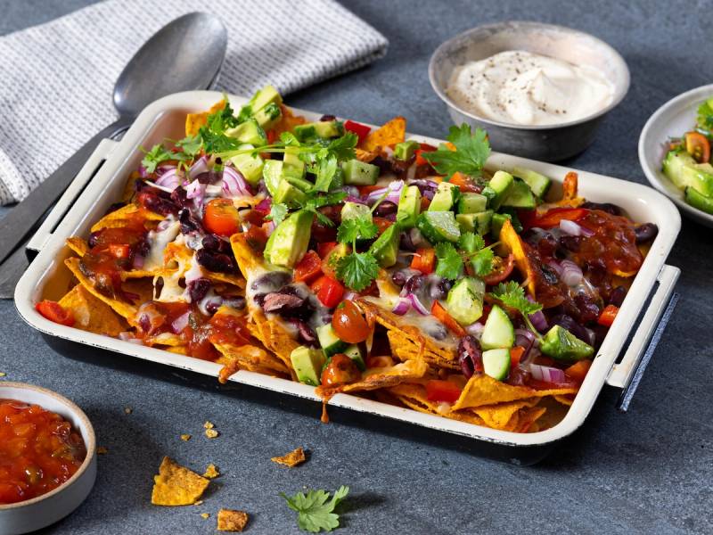 Vegie nachos med ost, grønnsaker og salsa på en hvit serveringsplate