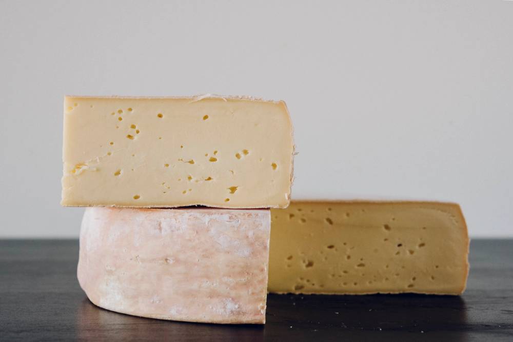 Tre ostestykker i ulike størrelser og farger ligger på en svart overflate mot en lys bakgrunn.