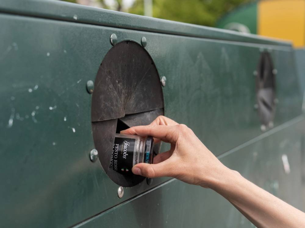 En person setter inn en mynt i en grønn betalingsautomat.