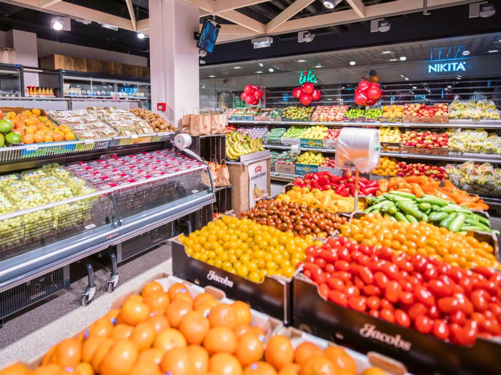 Fargerike frukt- og grønnsaksdisplayer i en matbutikk, med ulike typer tomater, bananer og sitroner.