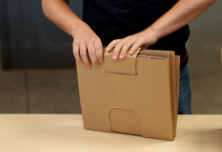 Person som åpner en pappeske på et bord.
