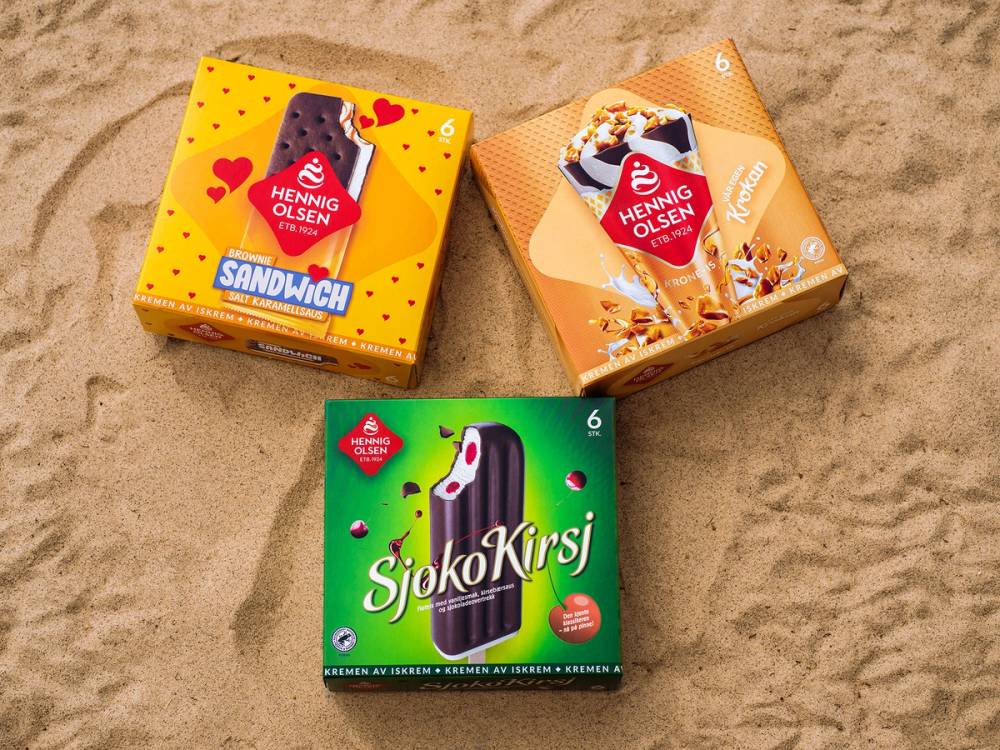 Tre esker med iskrem på sand, en med sjokolade og vanilje, en med karamell, og en med sjokoladekjeks, alle med Henning Olsen-logoen.