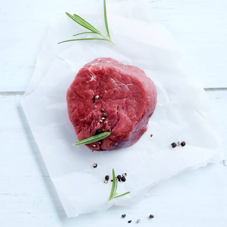 Indrefilet av biff med pepperkorn og urter på et hvitt underlag