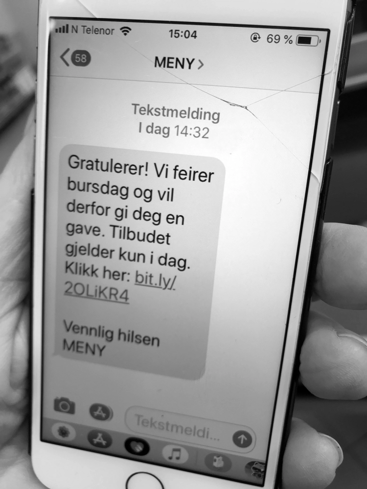 En mobilskjerm viser en tekstmelding som gratulerer med bursdagen og tilbyr en gave med en lenke, sannsynligvis en svindelmelding.