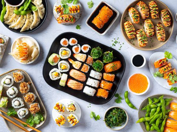 Variert utvalg av sushi på forskjellige tallerkener, inkludert nigiri, maki og ruller med grønnsaker og fisk.