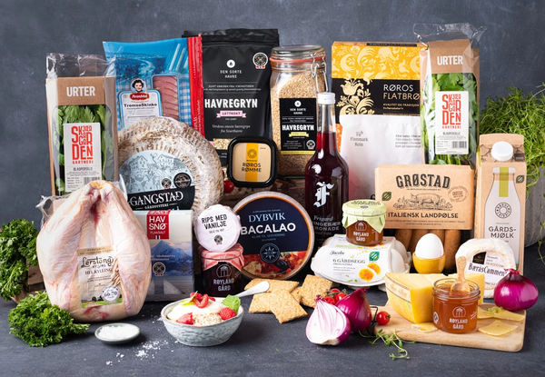 Et utvalg norske matvarer og produkter som ligger på en bordplate med en grå bakgrunn, inkludert kjøtt, egg, oster og krydder.
