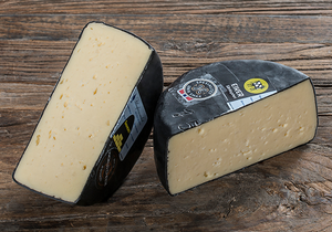 To stykker gruveost med svart skorpe på en treoverflate