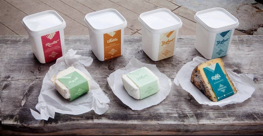 Førsteklasses ostekuber og emballasje på et bord, med fire ulike farger på emballasjen og ostekuber som er åpnet og delvis spist.