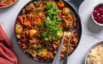 Høstgryte med grønnsaker og quinoa i en svart stekepanne, pyntet med frisk koriander