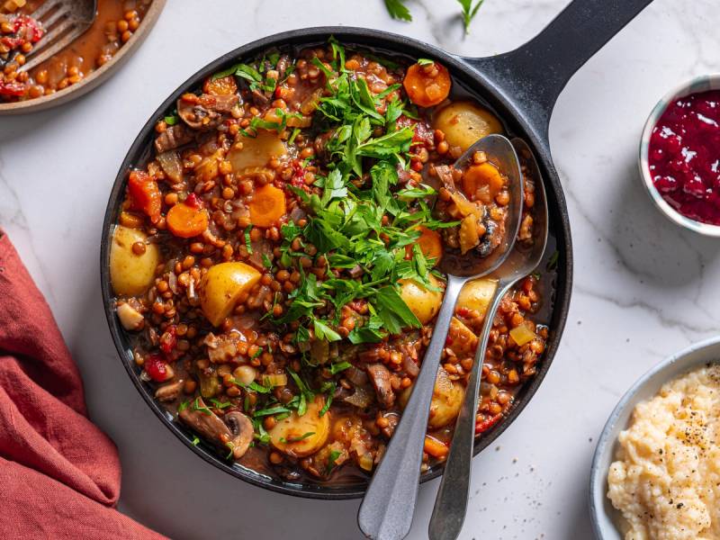 Høstgryte med grønnsaker og quinoa i en svart stekepanne, pyntet med frisk koriander
