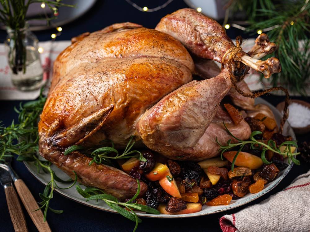 En stekt kalkun med fyldige bryster og ben, servert på et fat med grønnsaker og roser rundt, til nyttårsmiddag.