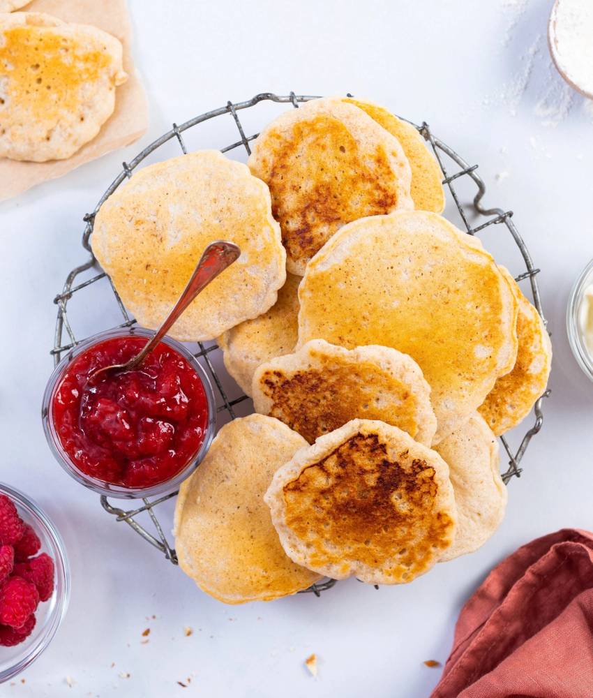 Ferske sveler på en avkjølt rist med en skål med jordbærsyltetøy ved siden av.