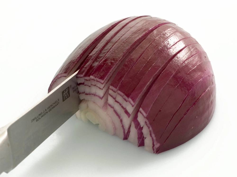 Skivet rød løk med hvite og lilla lag, klar til bruk i wok eller matlaging.