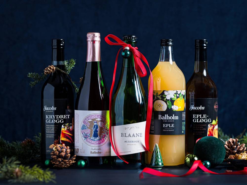 Flere flasker med alkoholholdige drikker og julepynt på et mørkt bord.