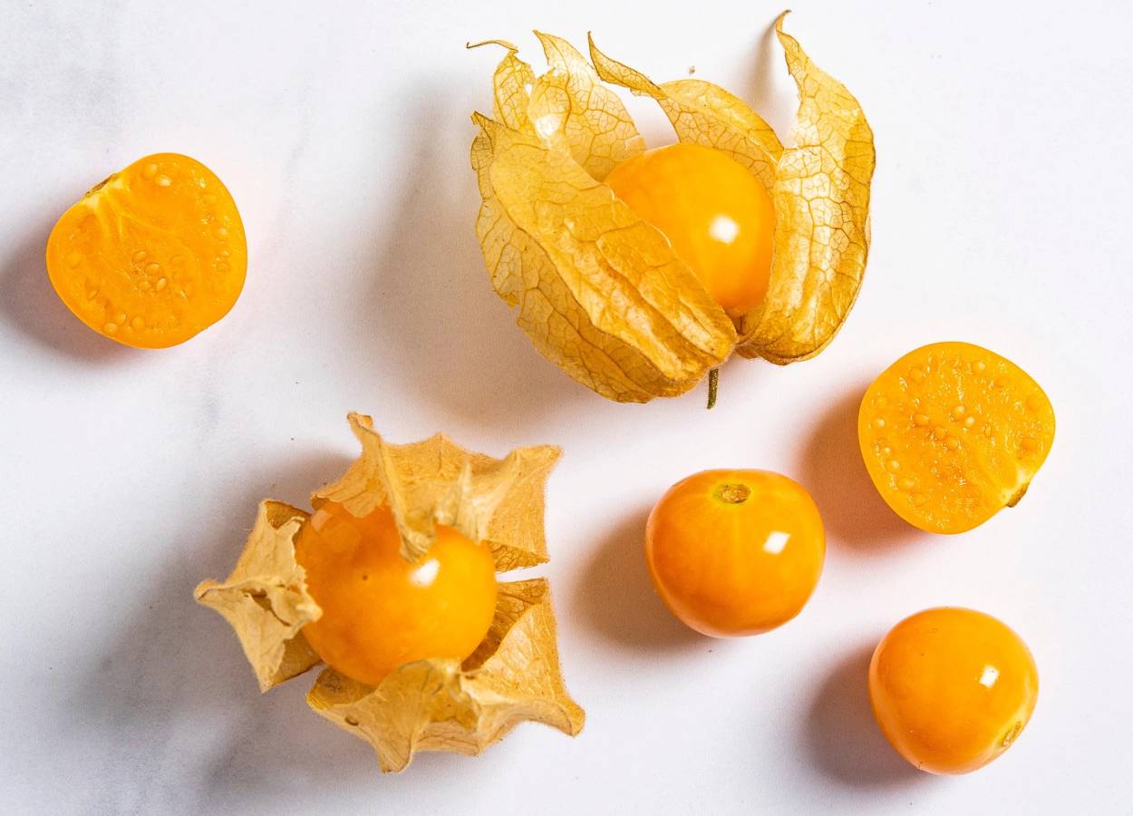 Physalis-frukt med sitt karakteristiske papiraktige omslag rundt den gule, runde frukten, plassert på en hvit bakgrunn.