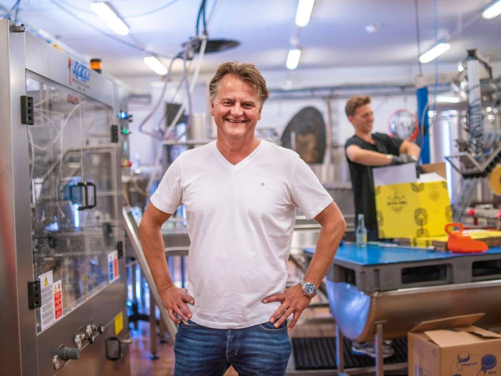 En person står med hendene på hoftene i et laboratorium eller verksted, omgitt av utstyr og maskiner.