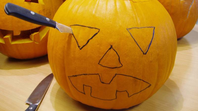 En stor gresskar med en skåret ansikt og en skisse av en trekantet øye, klar til å bli laget til en Halloween-lykt.