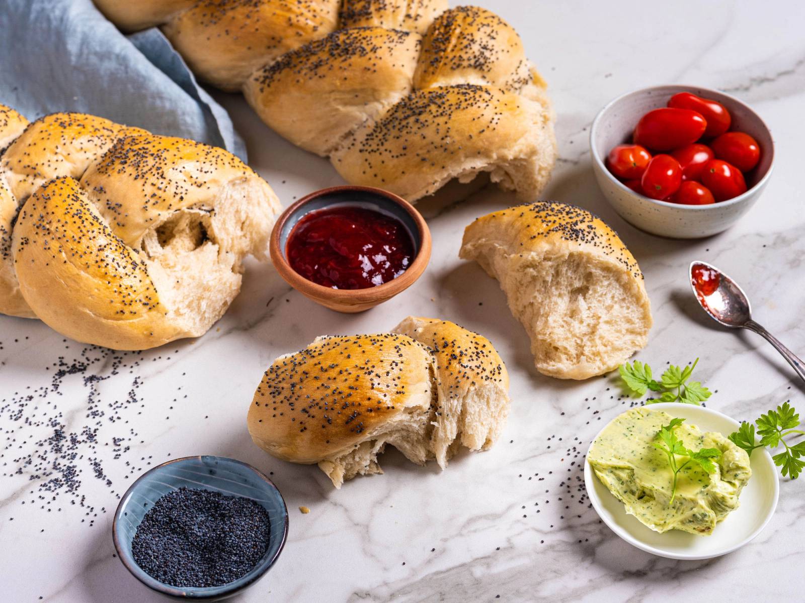 Fletteloff med ulike tilbehør som syltetøy, bær, salat og cherrytomater på en hvit overflate