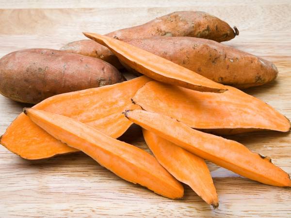 Skarne og hel søtpoteter ligger på et lyst trebord.