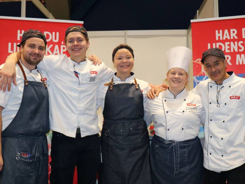 Fem personer står sammen på en scene under en prisutdeling for sjømathandlere i 2022, alle iført kokke- eller servitøruniformer.