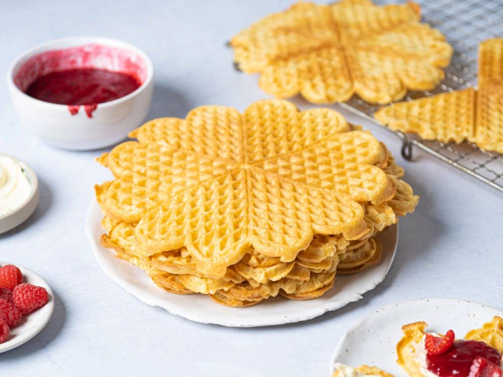 Vafler servert på en tallerken med jordbærsyltetøy og en skje ved siden av.