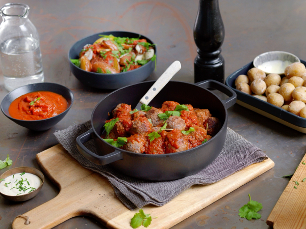 Et utvalg av tapasretter med kjøttboller, poteter og ulike sauser på et bord.