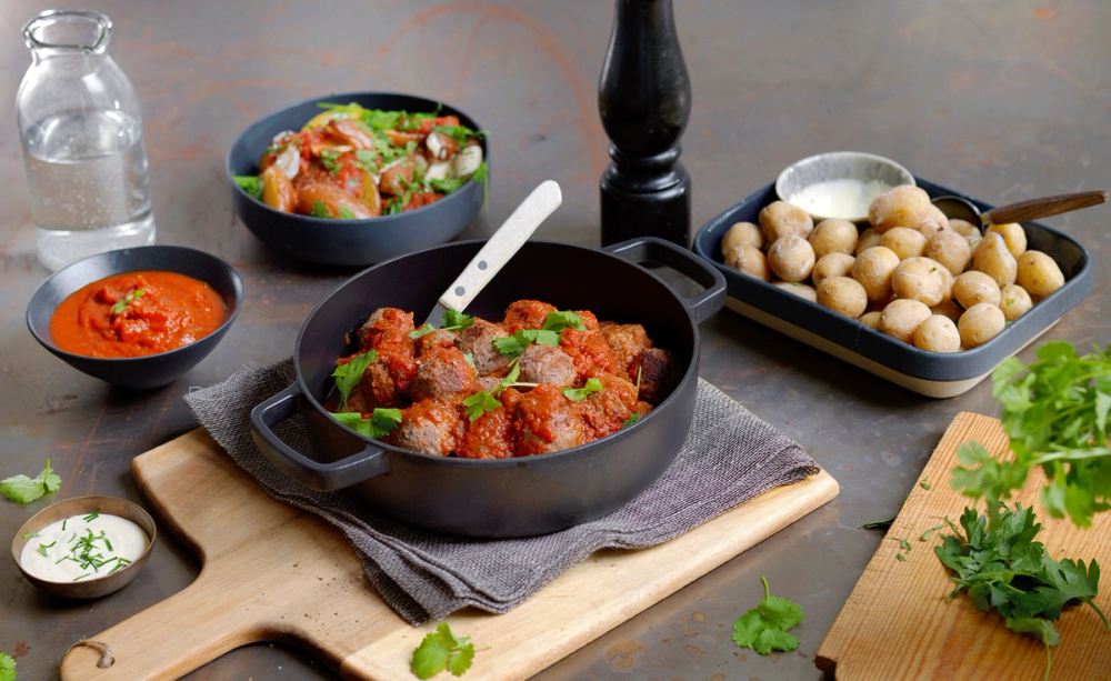 Et utvalg av tapasretter med kjøttboller, poteter og ulike sauser på et bord.