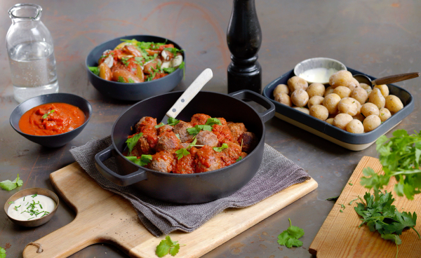 Et utvalg av tapasretter med kjøttboller, poteter og ulike sauser på et bord.