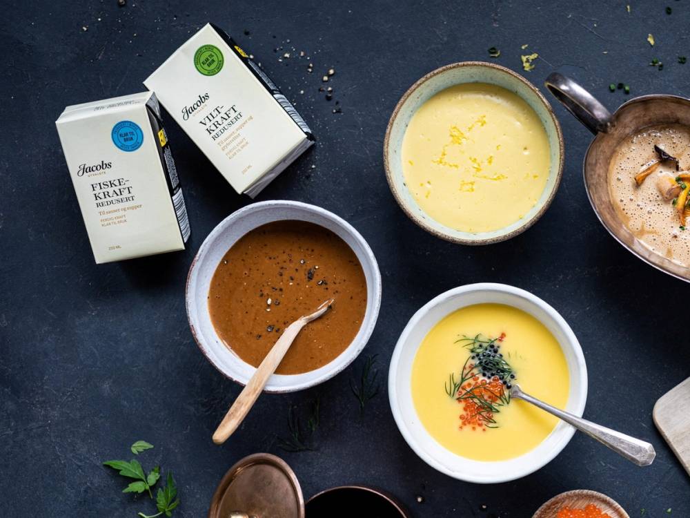 Ulike sauser i små skåler og kartonger med etiketter på en mørk bakgrunn, tydeligvis en utvalgt samling av sauser.