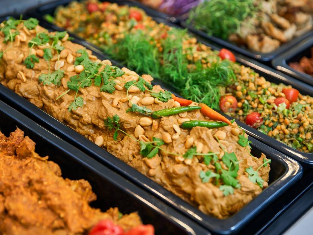 Vegetarisk rett med hakkede nøtter, urter og en liten chili på toppen, plassert i en serveringsform.