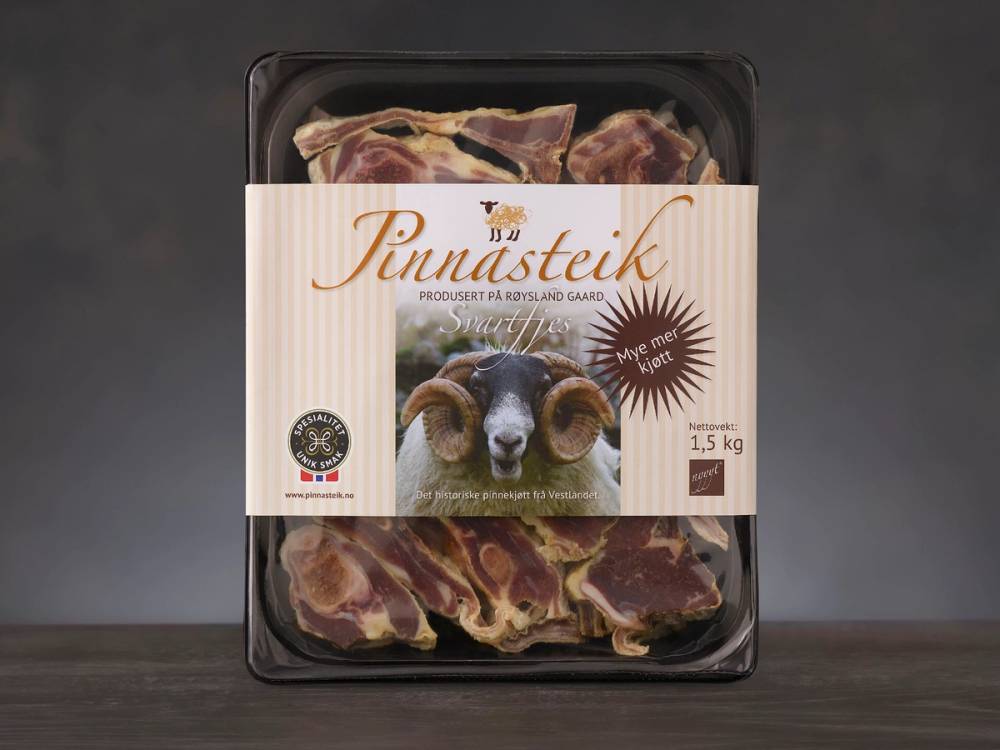 Pakke med pinnasteik med bilder av en hund og kjøtt på forsiden, plassert i en svart plastemballasje.