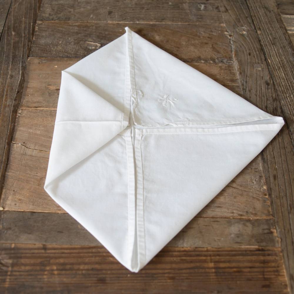 En hvit serviett brettet i en julestil på en treoverflate