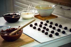 Sjokoladekaker og sjokoladeproduksjon med ulike sjokoladeprodukter og kuler på kjøkkenbenken.