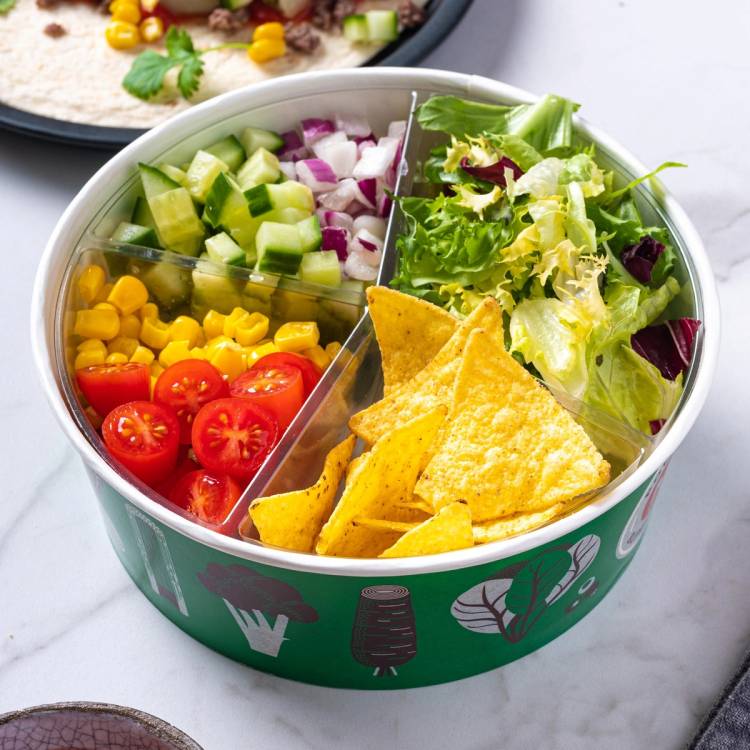 Salatbar med cherrytomater, agurk, rødløk, salat og tortilla chips i en rund boks.