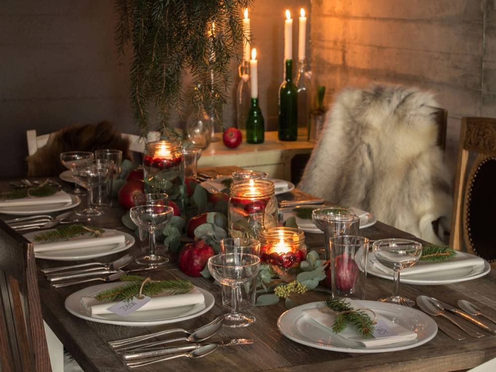 Et julebord med pyntede tallerkener, lys, og dekorasjoner, klar for festligheter.