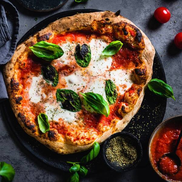 Pizza Margherita med tomatsaus, mozzarella og fersk basilikum på en steinplate