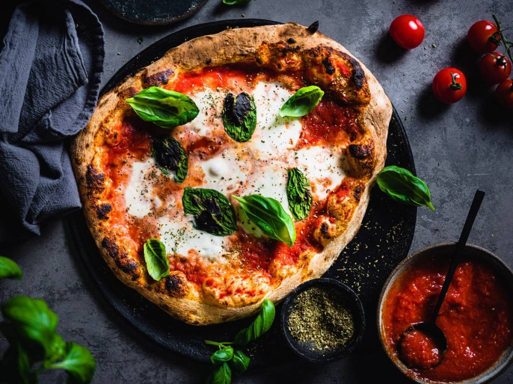 Pizza Margherita med tomatsaus, mozzarella og fersk basilikum på en steinplate