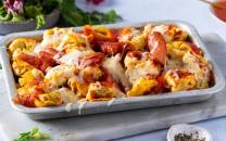 Pastagrateng med pølser, ost og tomatsaus i en ildfast form.