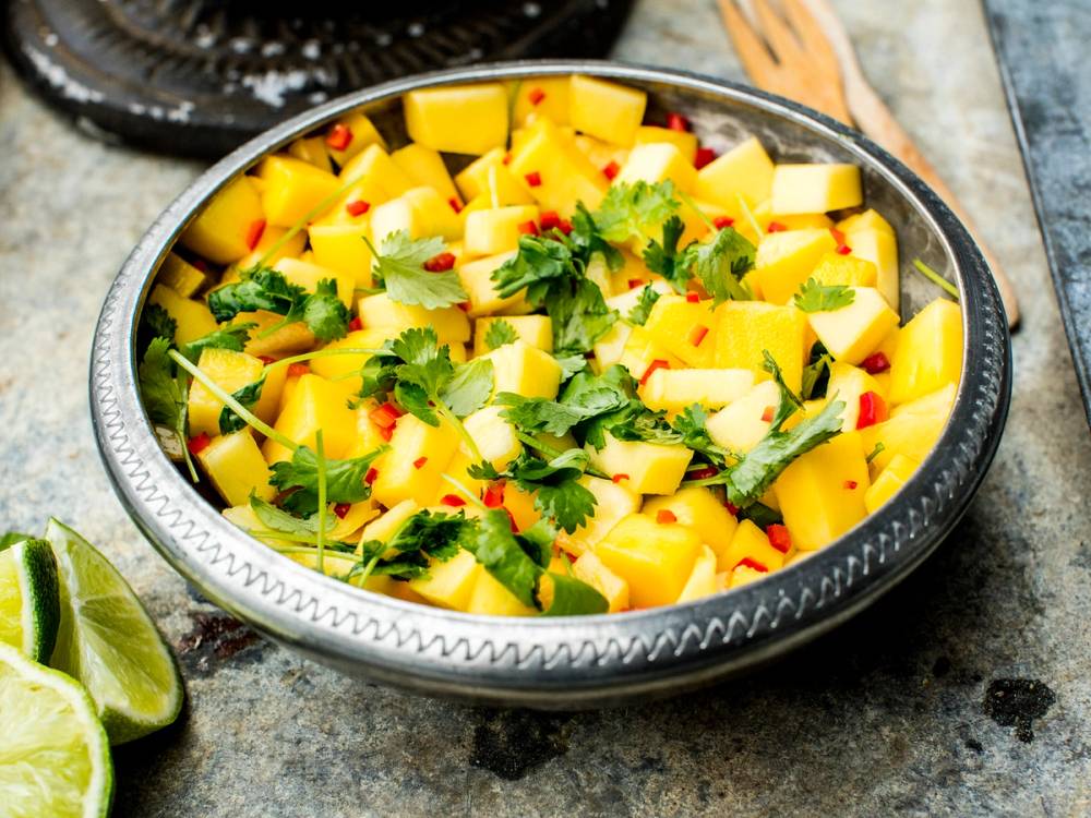 Mangosalsa med terninger av mango, koriander og små røde chili i en skål