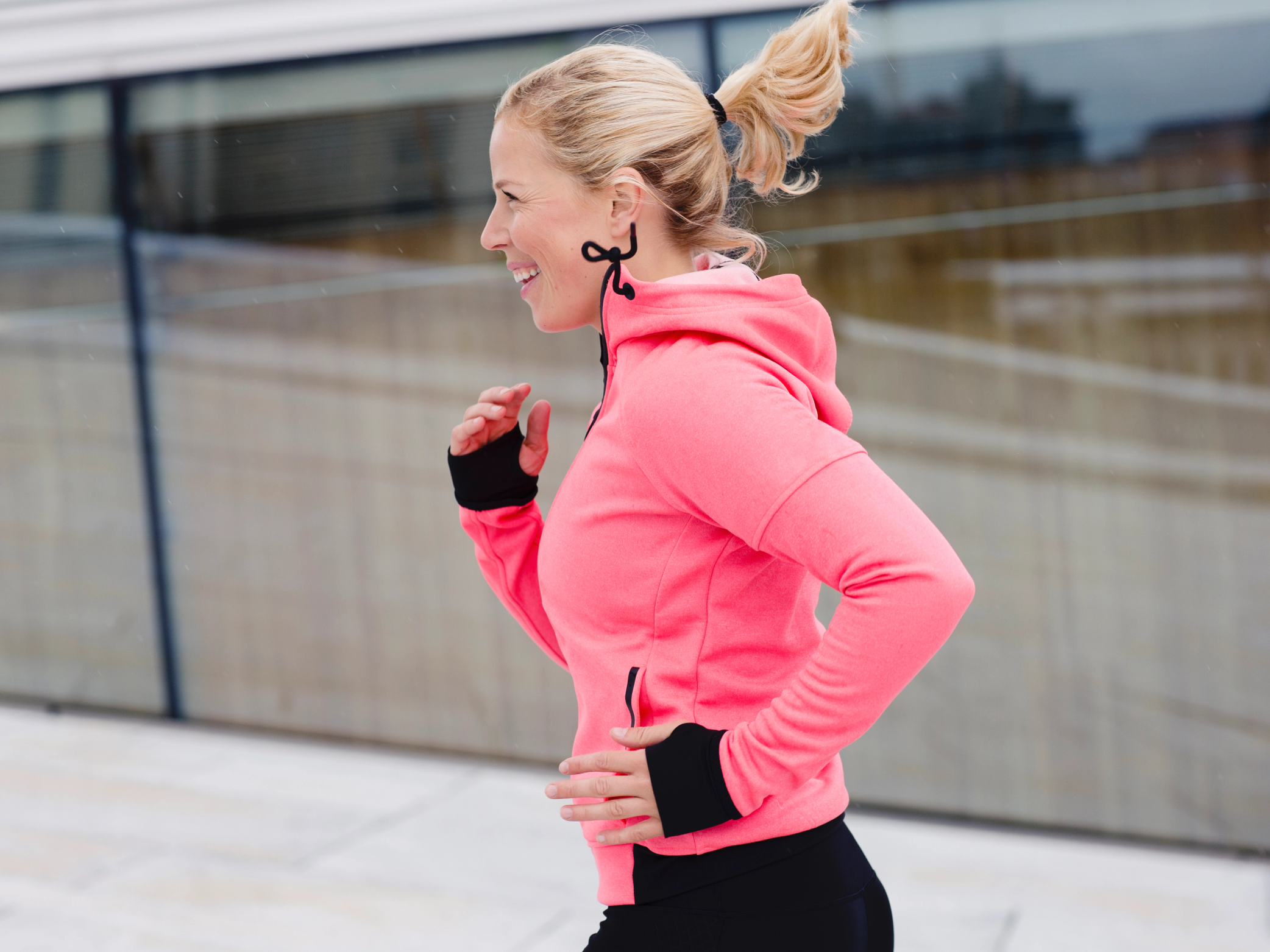 En kvinne i rosa treningsjakke løper utendørs under et maratonarrangement i Oslo.