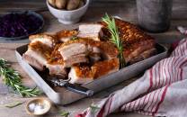 Skarer ribbe med sprø svor på et fat, omgitt av krydderurter og tilbehør.