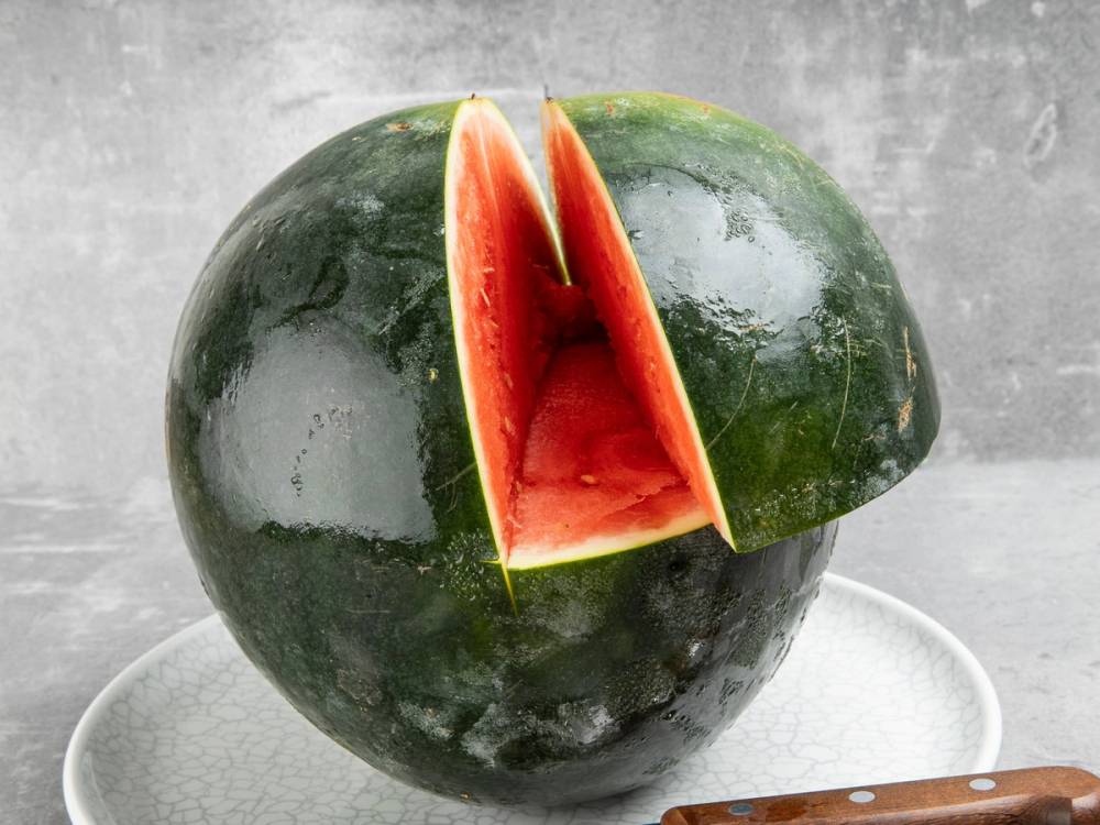 Vannmelon med et kutt som ligner en vogn, brukt til en babyshower, plassert på et bord.